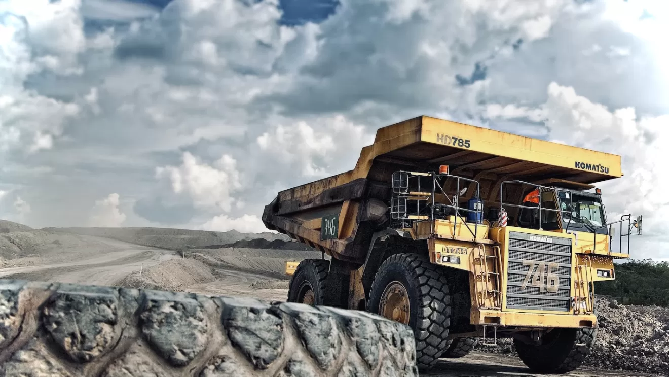 Quarry truck driving past large tyre